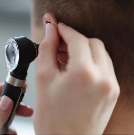 Doctor checking for ear infection in toddler or child.
