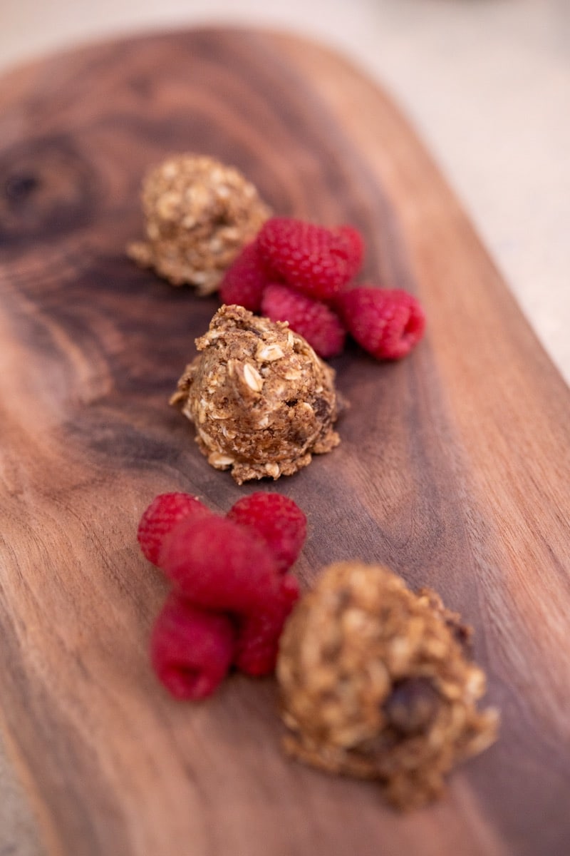 Finished anti-inflammatory protein balls on a walnut serving board with fresh raspberries