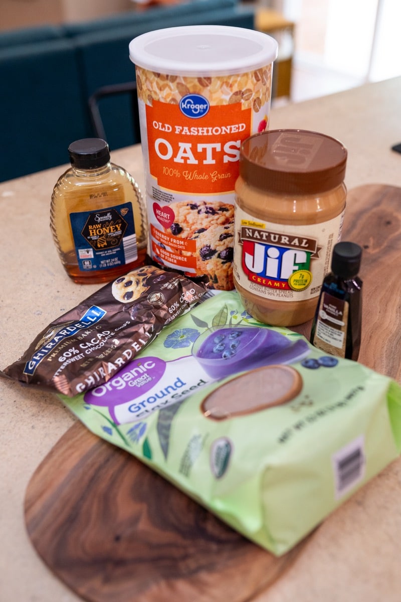 Ingredients for anti-inflammatory protein balls including rolled oats, peanut butter, vanilla, ground flaxseed and dark chocolate chips on a kitchen counter