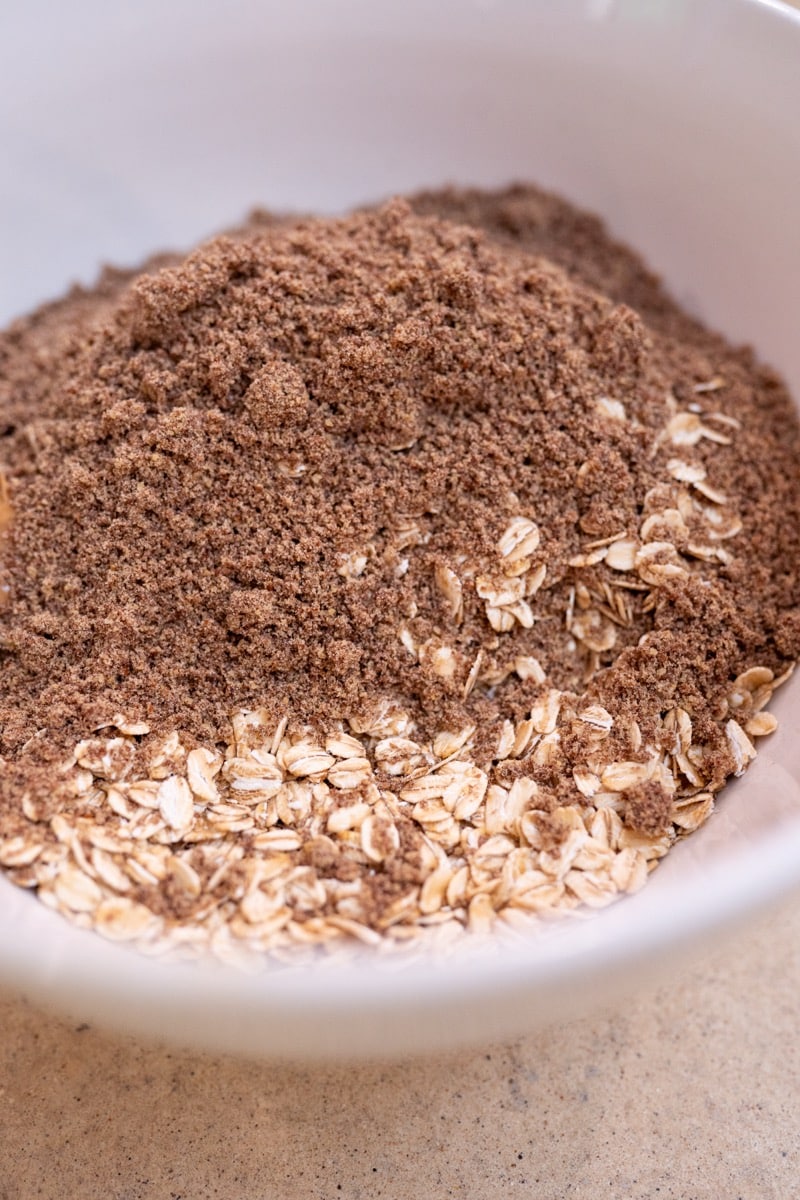 Rolled oats, cinnamon and ground flaxseed in a white bowl before mixing