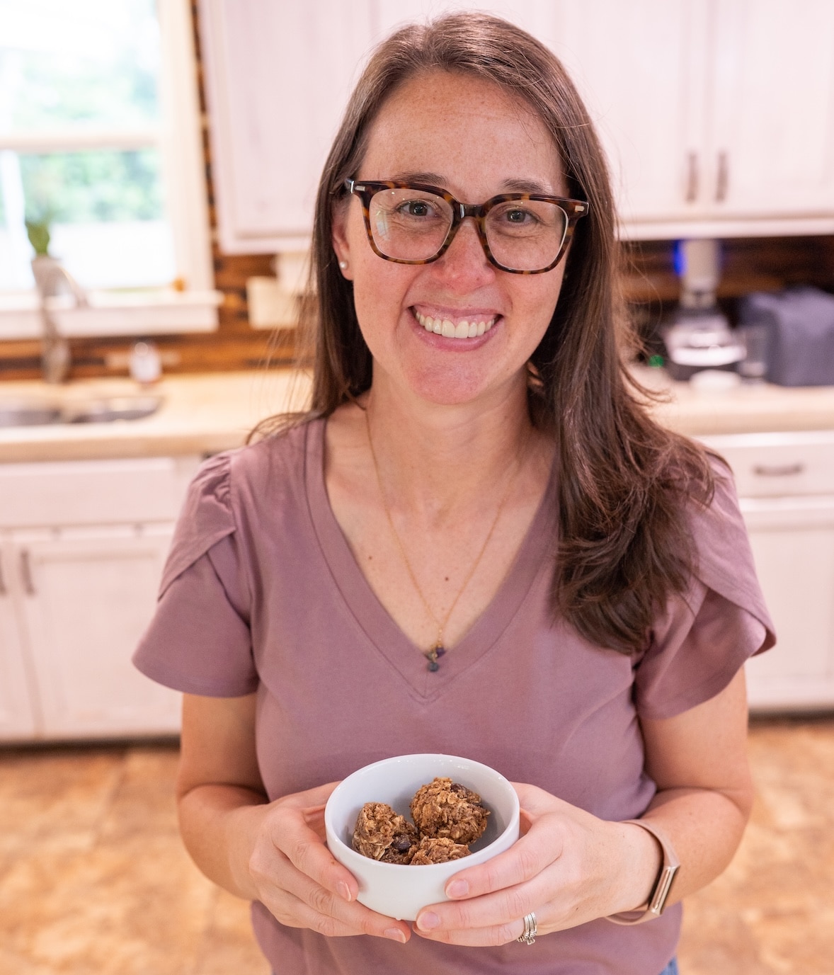 Registered dietitian Sarah Bullard holding a bowl of homemade anti-inflammatory no-bake energy bites in her kitchen.
