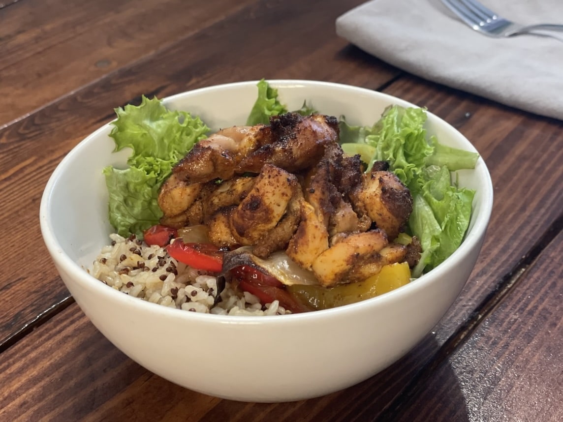 Sheet pan chicken fajita bowl with greens, peppers, onions, and whole grains.