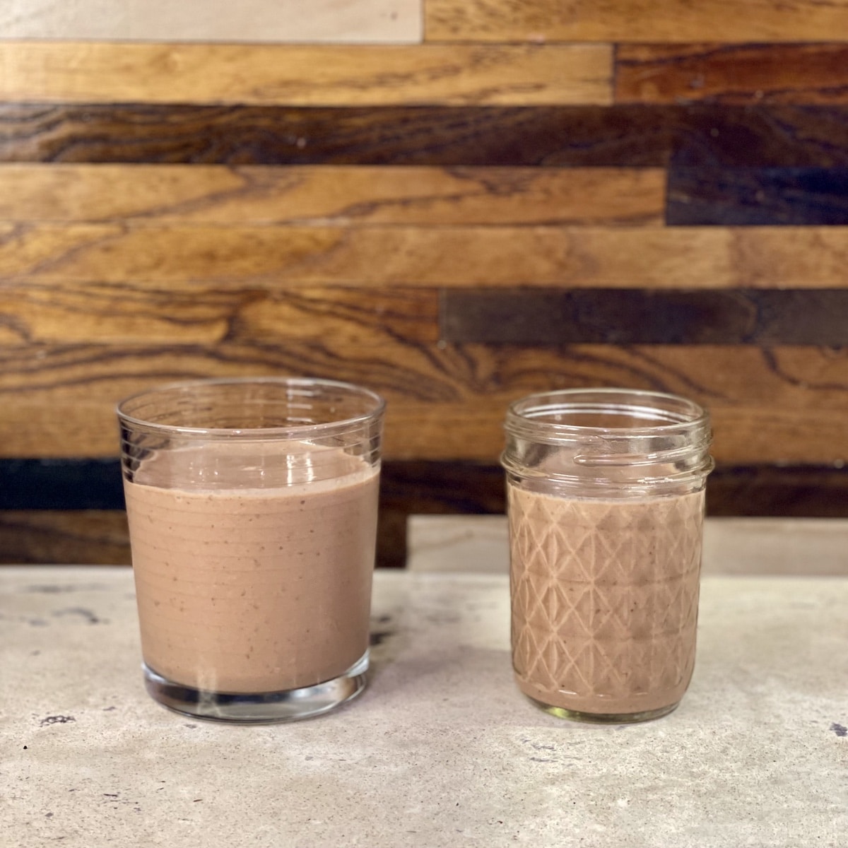 Chocolate banana smoothie served in two glasses on a kitchen counter, made with kefir, cocoa, banana and peanut butter
