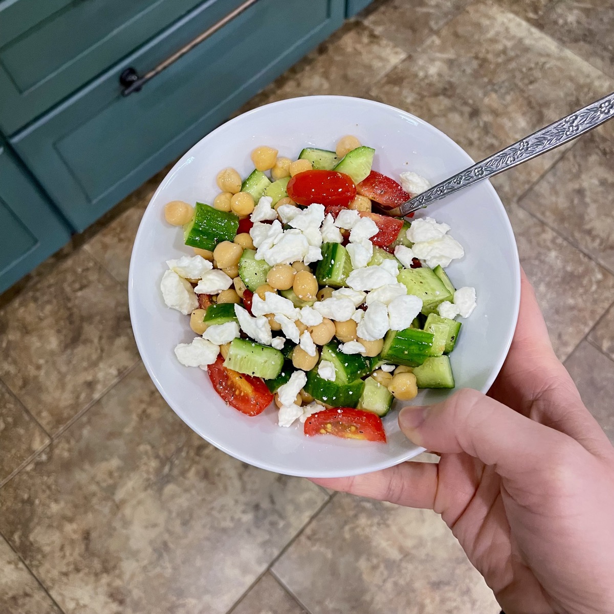 Mediterranean chickpea salad with tomatoes, cucumber and feta in a white bowl