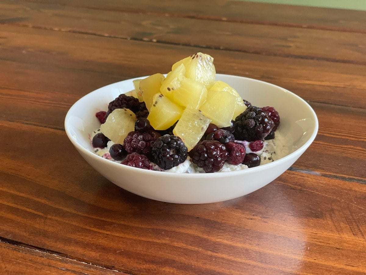 Greek yogurt topped with frozen mixed berries and diced golden kiwi