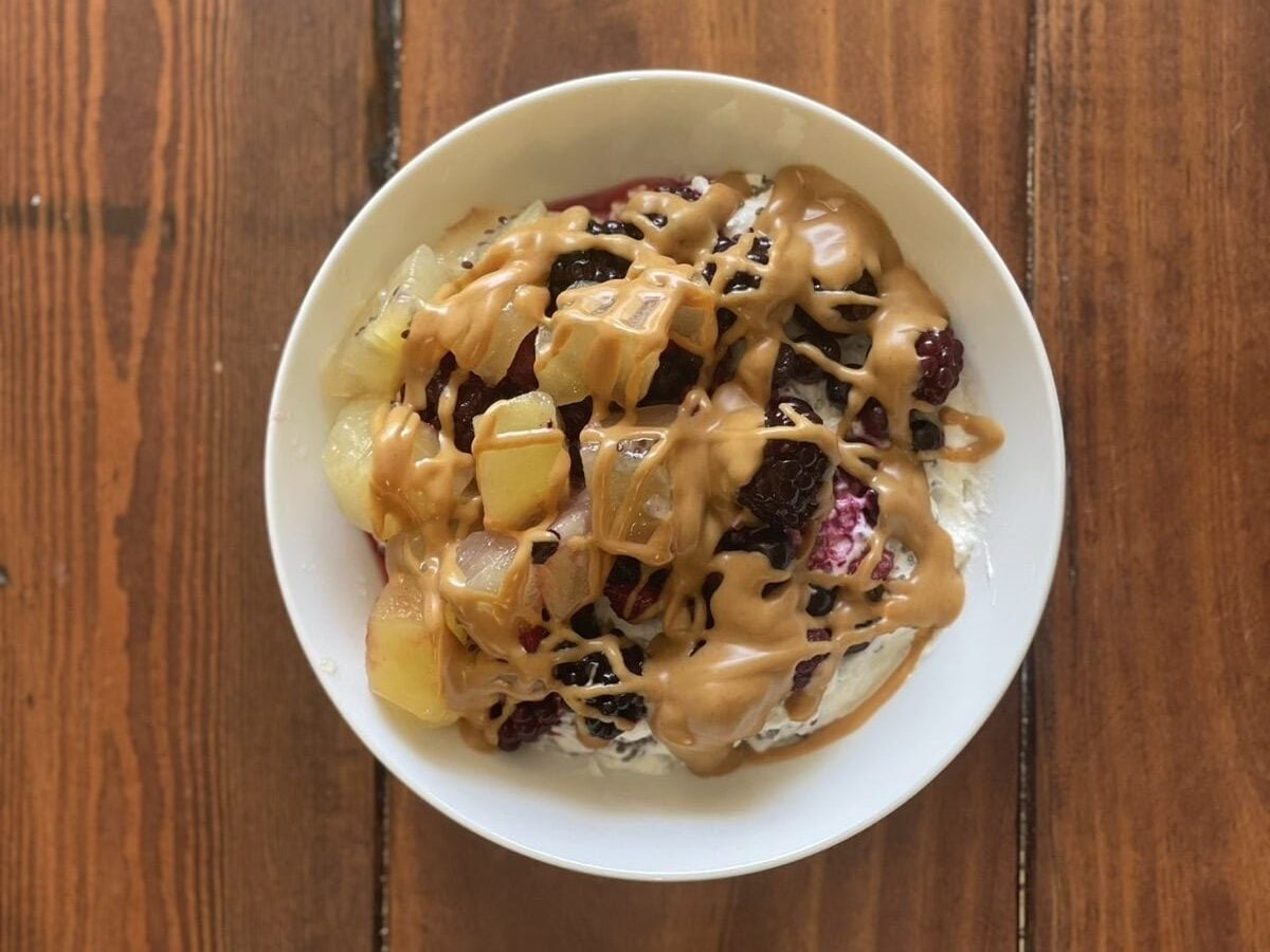Greek yogurt bowl with mixed berries, golden kiwi and a peanut butter drizzle, viewed from above