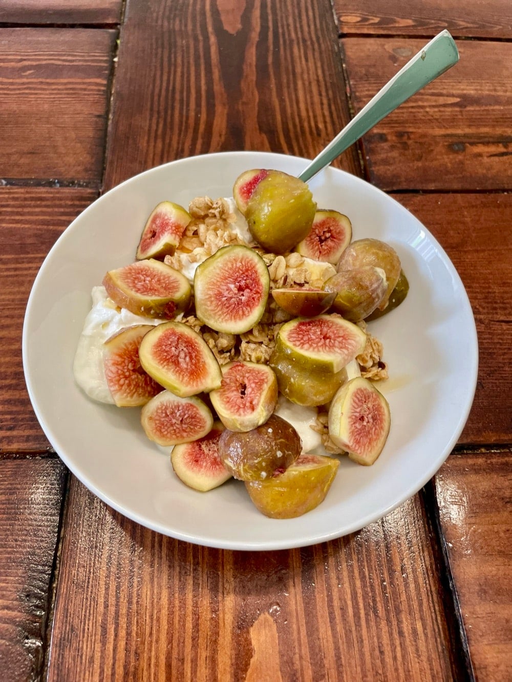 Greek yogurt bowl with fresh figs, pumpkin granola and a honey drizzle, side view