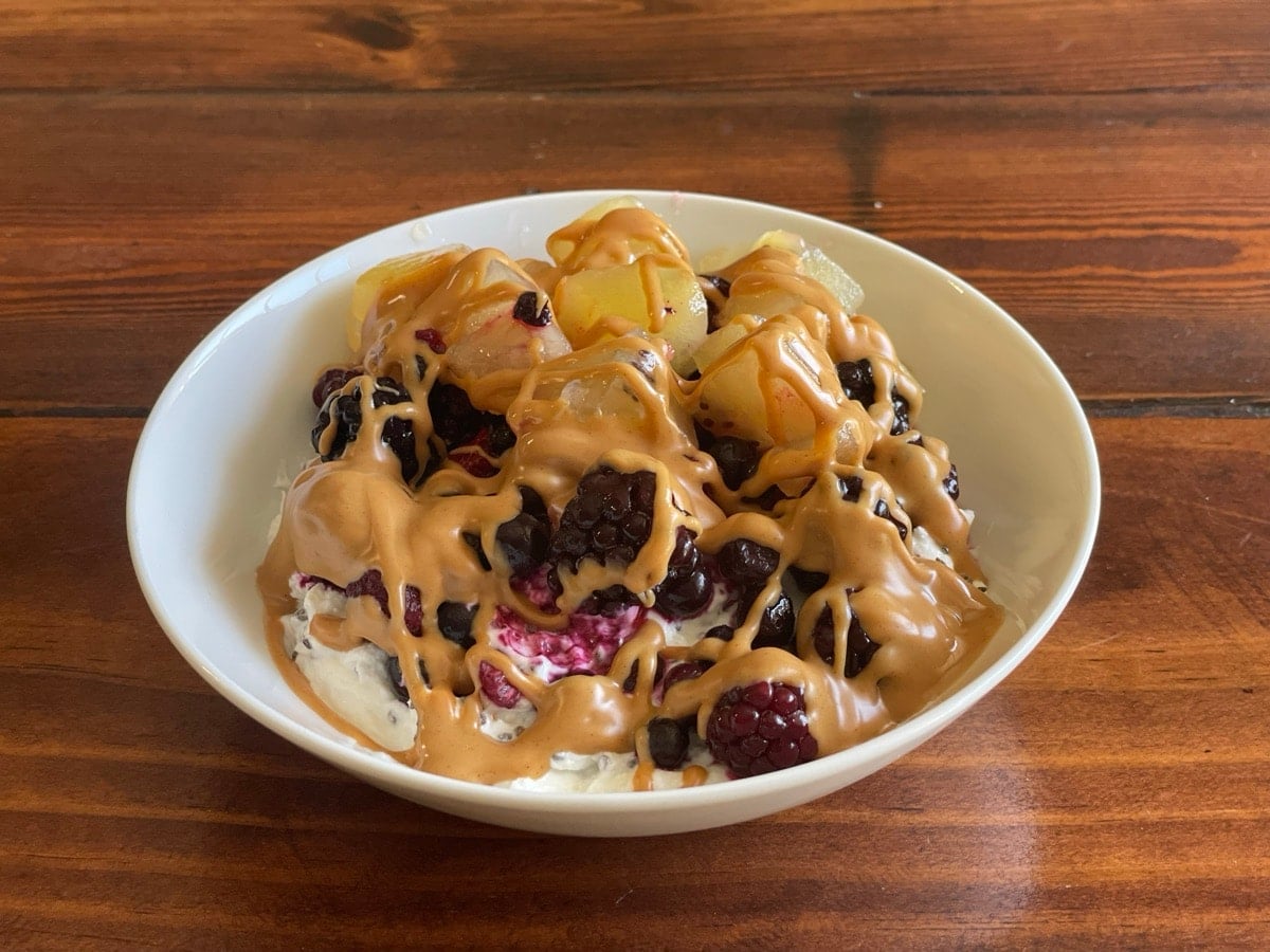 Side view of a Greek yogurt bowl with berries, golden kiwi and a peanut butter drizzle
