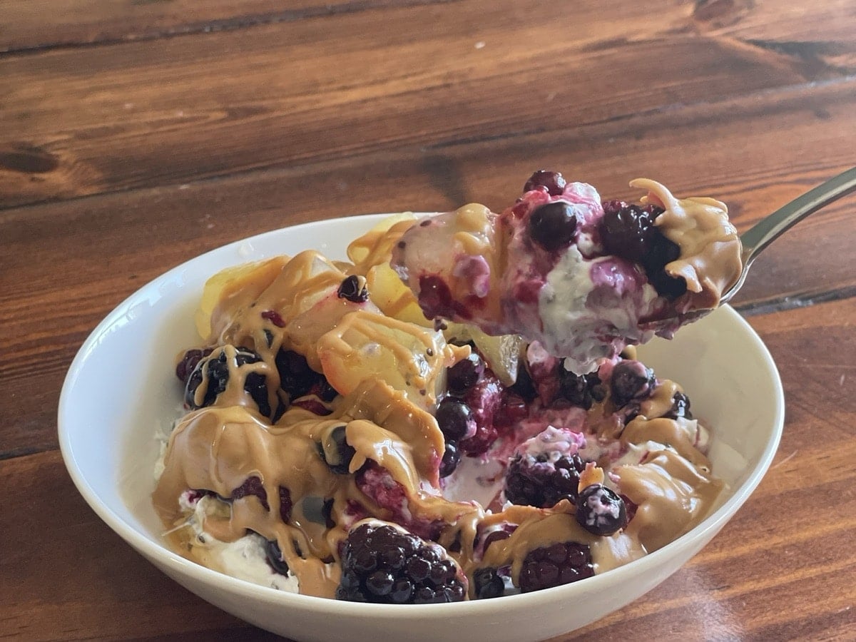 Spoonful of Greek yogurt swirled with berry juice and peanut butter lifted from the bowl
