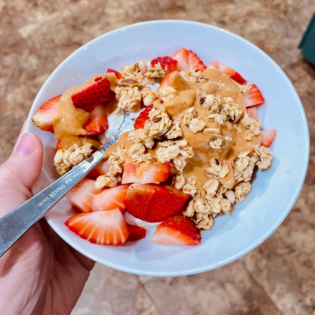 Greek yogurt bowl with fresh strawberries, granola and a peanut butter drizzle