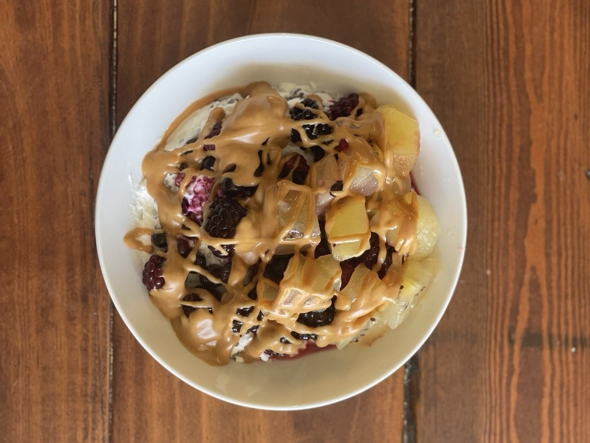 Greek yogurt bowl with mixed berries, golden kiwi and a peanut butter drizzle, viewed from above